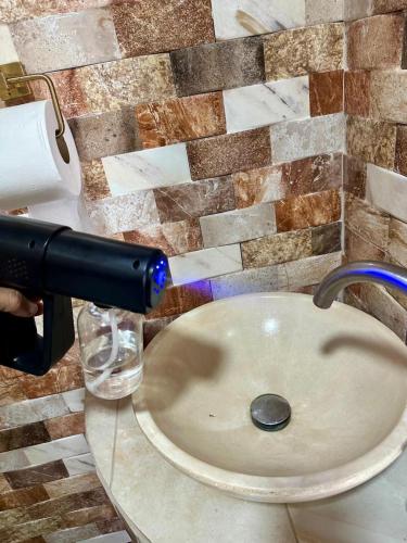 a person is washing a sink in a bathroom at Hospedaje Nacho y Ale No 1, Paso Canoas, Costa Rica in Canoas