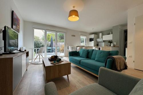 un salon avec un canapé bleu et une cuisine dans l'établissement Apartment 5 minutes from the beach, à Lion-sur-Mer