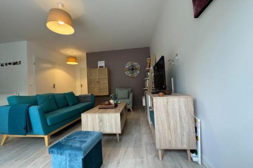 un salon avec un canapé bleu et une table dans l'établissement Apartment 5 minutes from the beach, à Lion-sur-Mer