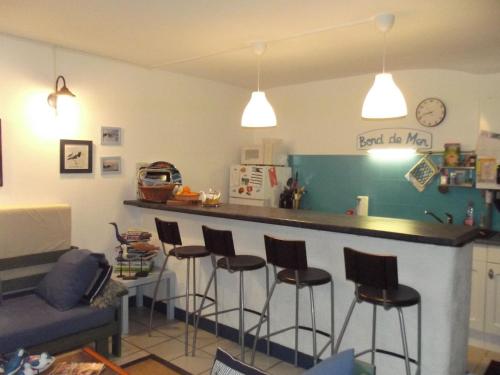 - une cuisine avec un bar avec des tabourets et un canapé dans l'établissement Agreable maison de pecheur a 2 pas du port, à La Trinité-sur-Mer