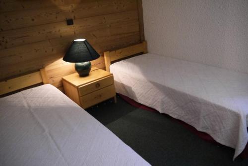 une chambre avec deux lits et une lampe sur une table de chevet dans l'établissement Résidence Nantchu - NANTCHU 21 MAE-4391, à Les Allues