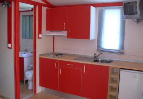 una piccola cucina con armadi rossi e lavandino di Parque de Campismo Orbitur Valverde a Luz