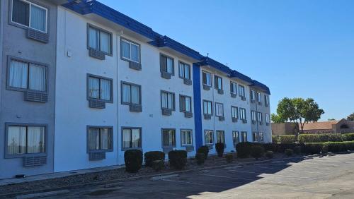 un bâtiment blanc avec des fenêtres et des buissons à côté d'une rue dans l'établissement MetroParc 'nSuites, à Stockton