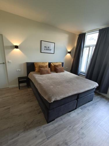 a bedroom with a large bed with pillows on it at Mooi en trendy appartement vlakbij strand in Vlissingen