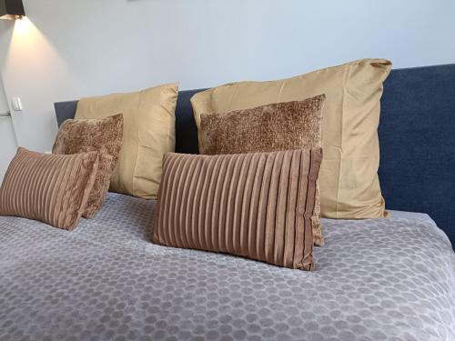a bed with four pillows on top of it at Mooi en trendy appartement vlakbij strand in Vlissingen