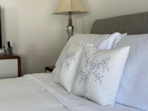 a bed with white pillows on it with a lamp at New Tropical Island Ohana near Beach with community Pool Spa Gym PingPong and more in Waianae