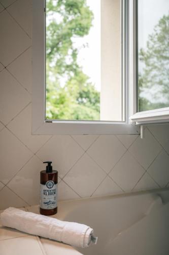 a bottle of soap sitting on a counter next to a window at Le levant de Cremens in Magnan