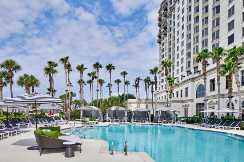 a pool at the resort with chairs and palm trees at The Westin Savannah Harbor Golf Resort & Spa in Savannah