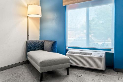 a chair and a window in a room with a heater at Holiday Inn Express & Suites Detroit - Novi by IHG in Novi