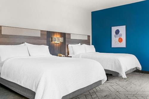 two beds in a hotel room with blue walls at Holiday Inn Express & Suites Detroit - Novi by IHG in Novi