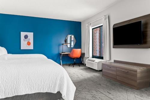 a blue bedroom with a bed and a tv at Holiday Inn Express & Suites Detroit - Novi by IHG in Novi