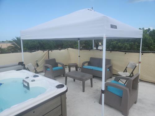 a group of chairs sitting under a white umbrella at Stargaze Comfort Under the Stars & Arcade Room in Aguadilla