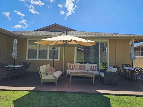 a patio with an umbrella and chairs and tables at New Tropical Island Ohana near Beach with community Pool Spa Gym PingPong and more in Waianae