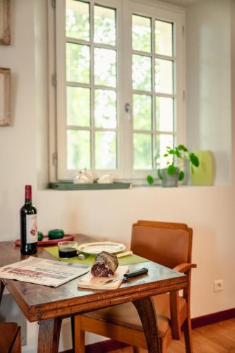 a table with a bottle of wine and a window at Le levant de Cremens in Magnan