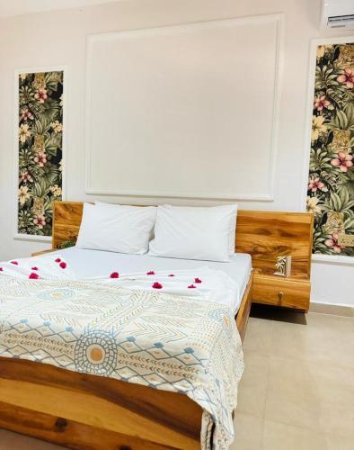 a bedroom with a bed with white sheets and red flowers on it at Sand and Sunset in Kendwa