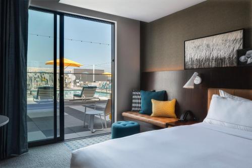 a hotel room with a bed and a view of a patio at Hilton Buena Park Anaheim in Buena Park