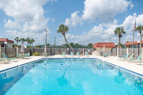 a large swimming pool with chairs and palm trees at Coastal Condo - Walk to Beach Pool Pickleball and Boat Ramp in Saint Augustine