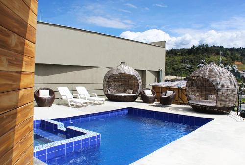a house with a swimming pool and chairs and a building at Beverly Hills Mansion room only in Guarne