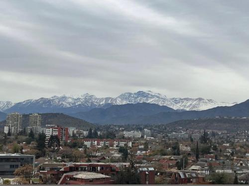 a city with snow covered mountains in the background at Dept Hermosa Vista, Las Condes in Santiago