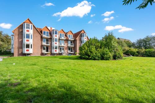 an apartment building on a grassy field in front at Küstenperle Nordsee mit Balkon und Sauna in Cappel-Neufeld