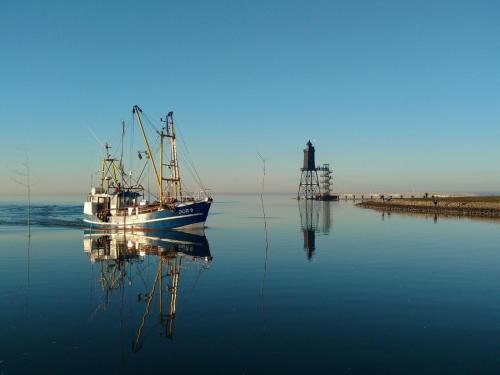 a boat sitting in the water with its reflection at Küstenperle Nordsee mit Balkon und Sauna in Cappel-Neufeld