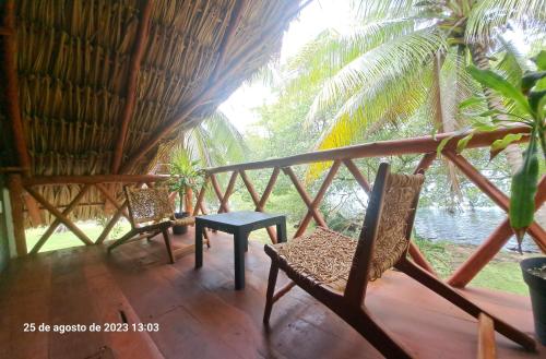 two chairs and a table on the porch of a hut at Xanthus Hotel in Huay Pix
