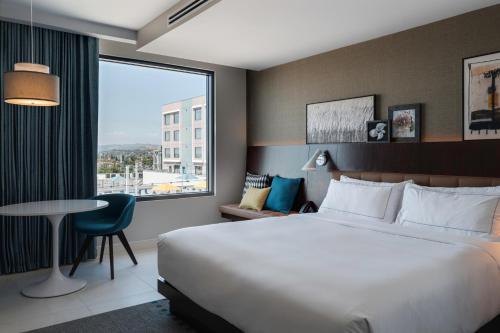 a hotel room with a bed and a table and a window at Hilton Buena Park Anaheim in Buena Park