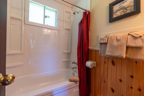 a bathroom with a white tub and a red shower curtain at Blue Water Acres in Huntsville
