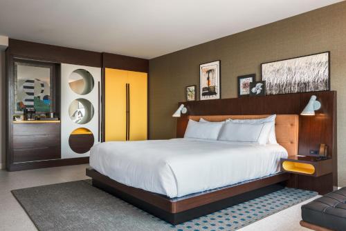 a bedroom with a large bed with white sheets at Hilton Buena Park Anaheim in Buena Park
