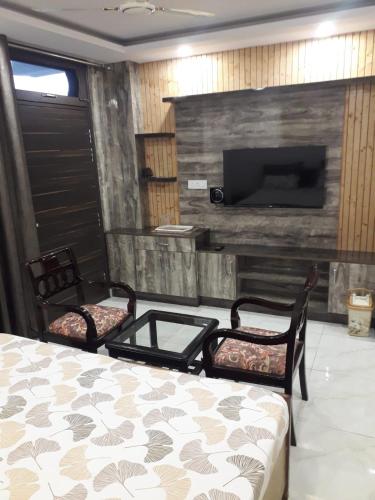 a bedroom with a bed and two chairs and a tv at Hazelwood Kandaghat in Kandāghāt