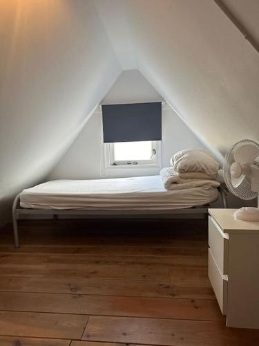 a bedroom with a bed with a window in a attic at Garden house, Free parking in Zandvoort