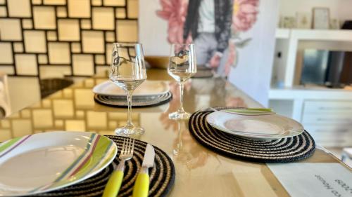 a table with two wine glasses and plates on it at Ñireco HOUSE in San Carlos de Bariloche