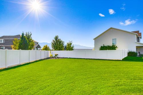 a white fence in a yard with a house at Utah Retreat with Patio, Gas Grill and Mountain Views! in Logan