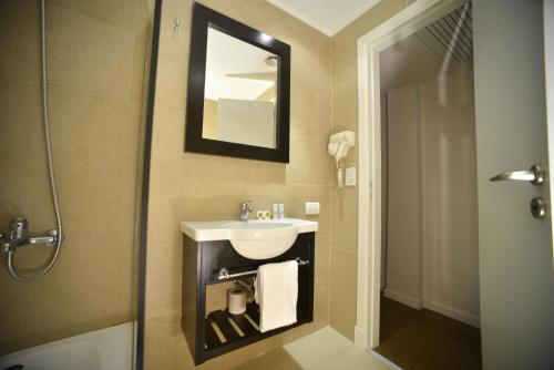 y baño con lavabo y espejo. en Hotel Versailles en Mar del Plata