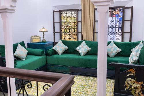 a living room with a green couch and stained glass windows at Iguana Azul in Chefchaouene