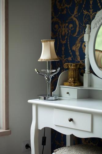 a dressing table with a lamp and a mirror at Piejūras apartamenti STEAMER in Roja