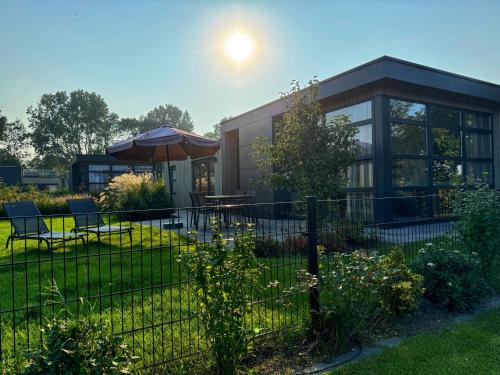 a house with a fence and a table and an umbrella at Enkhuizer Strand Chalet Wellenreiter Zweite Reihe Haus Nr 213 in Enkhuizen