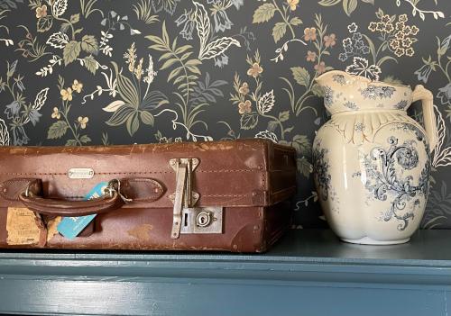 a briefcase and a vase sitting on a shelf with a suitcase at The Reverie - a place to rest in Kyneton