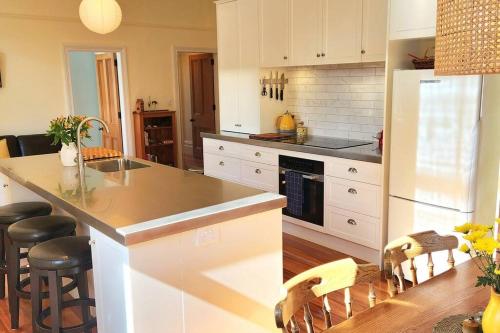 a kitchen with white cabinets and a kitchen island with stools at Luxury new 3 bedroom house in central city 5 star in Christchurch