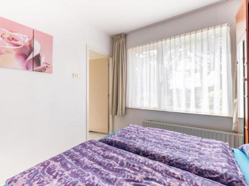 a bedroom with a purple bed and a window at Zonnehoek in Exloo