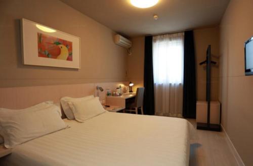 a bedroom with a white bed with a desk and a window at Jinjiang Inn - Changchun Convention & Exhibition Center in Changchun