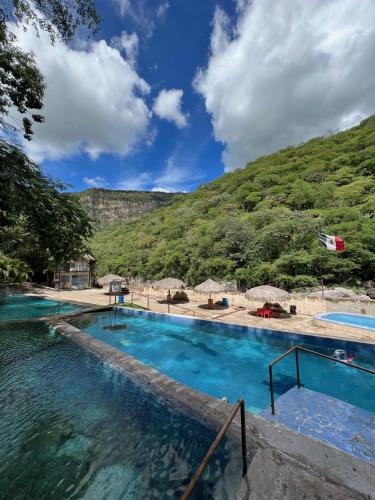 a swimming pool with a mountain in the background at Rancho El Venado Termales in Acatic