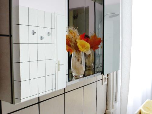 un bagno con un vaso di fiori in uno specchio di Manoir 19e 7 chambres, piscine chauffée, parc arboré proche lac en Champagne - FR-1-611-95 a Montier-en-Der