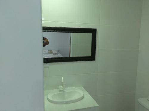 a white bathroom with a sink and a mirror at Pousada mirante por do sol in Niterói