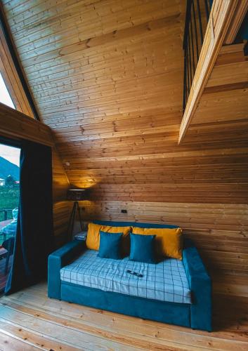 a blue couch in a room with a wooden ceiling at Gold cottages Kazbegi in Kazbegi
