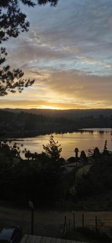 a view of a lake with the sun setting in the distance at Hermosa cabaña con vista al lago Vichuquén in Vichuquén