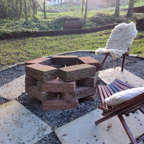 a pile of bricks next to a chair and a fire pit at Cabana Das Paineiras in Feliz