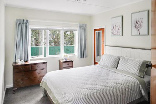 a bedroom with a bed and two windows at Whitianga Blue Bach - Location Location Location! in Whitianga