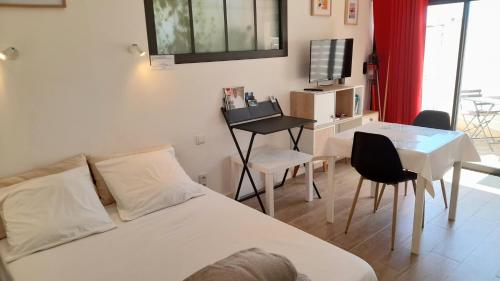 une chambre avec un lit, une table et une télévision dans l'établissement Studio logement entier calme neuf climatisé avec extérieur, à Puget-Ville