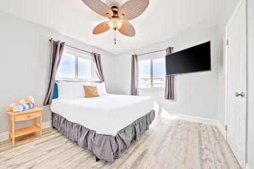 a white bedroom with a bed and a ceiling fan at Balboa Peninsula Hidden Gem with Private Balcony & Stunning Views in Newport Beach
